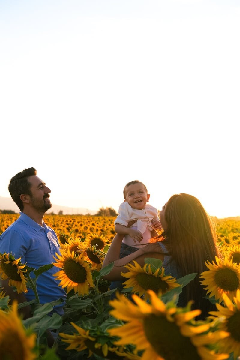 A joyful family moment captured in a vibrant sunflower field during sunset.